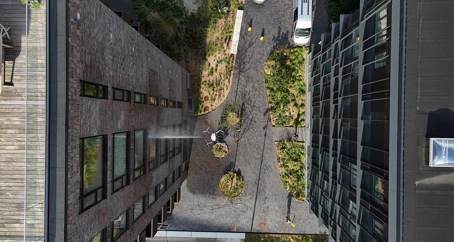 Overhead-view af High-DRA drone der renser gårdfacade